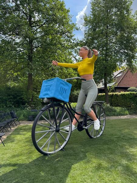 Kunstwerk van vier meter hoog van een jonge vrouw op de fiets met een mandje voorop